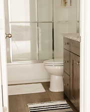 Full bath featuring vanity and shower / bath combination with glass door