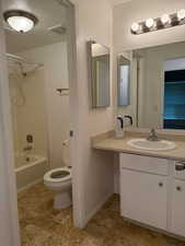 Bathroom with a textured ceiling, shower / washtub combination, and vanity