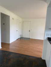Unfurnished dining area featuring crown molding and dark wood-type flooring