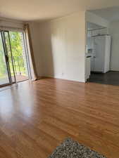Unfurnished living room featuring dark wood-style flooring and ornamental molding