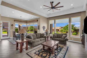 Living room featuring healthy amount of natural light, light wood-type flooring, a raised ceiling, and recessed lighting