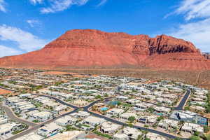 Aerial view of property and surrounding area featuring nearby suburban area and a mountain backdrop