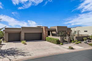 Adobe home featuring a gate, stucco siding, stone siding, and an attached garage