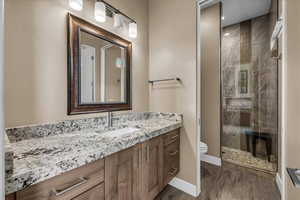 Full bath featuring vanity, a shower stall, and dark wood-type flooring