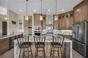 Kitchen featuring light stone counters, appliances with stainless steel finishes, decorative backsplash, a center island, and a kitchen bar