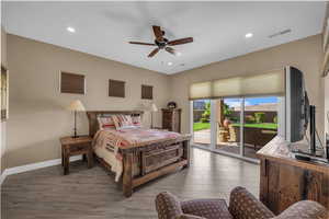 Bedroom featuring wood finished floors, access to exterior, a ceiling fan, and recessed lighting