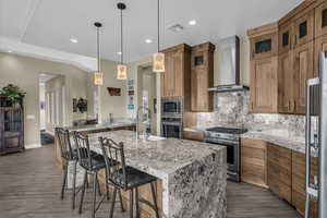 Kitchen with tasteful backsplash, stainless steel appliances, brown cabinets, pendant lighting, and recessed lighting