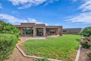 Back of property with stucco siding, a lawn, and a patio area