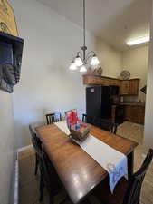 Dining area featuring light tile patterned floors, a chandelier, and lofted ceiling