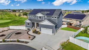 View of front of home with roof mounted solar panels, a residential view, driveway, a shingled roof, and an attached garage