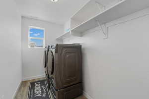 Laundry room with washer and clothes dryer and light wood finished floors