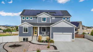 View of front facade featuring covered porch, concrete driveway, solar panels, a garage, and board and batten siding
