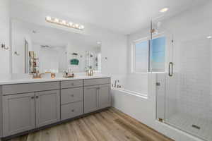 Full bath featuring a garden tub, double vanity, a shower stall, light wood-style floors, and recessed lighting
