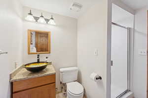 Full bath with vanity, a shower stall, and a textured ceiling