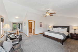 Bedroom with vaulted ceiling, carpet, a ceiling fan, and a textured ceiling