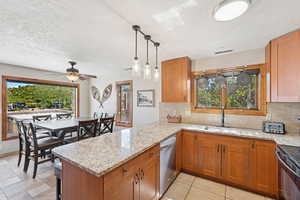 Kitchen featuring tasteful backsplash, brown cabinets, light stone counters, a peninsula, and a textured ceiling