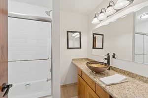 Bathroom featuring light tile patterned flooring, vanity, and shower / bath combination with glass door