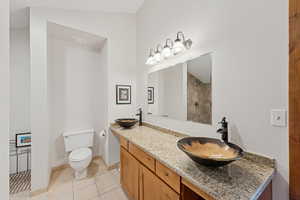 Full bath with double vanity, light tile patterned floors, and a tile shower