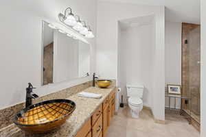Bathroom with light tile patterned floors, double vanity, and a tile shower