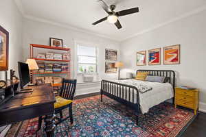 Bedroom featuring crown molding, dark wood-style floors, ceiling fan, and a desk