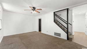 Carpeted empty room with a textured ceiling, stairs, and a ceiling fan