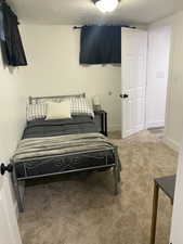 Bedroom with a textured ceiling and light carpet