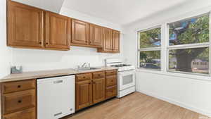 Kitchen featuring white appliances, light countertops, light wood-type flooring, and brown cabinets