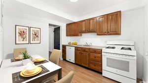 Kitchen featuring white appliances, light countertops, brown cabinets, and light wood-style floors