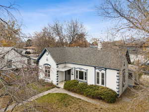 View of front of property featuring roof with shingles, stucco siding, and a chimney