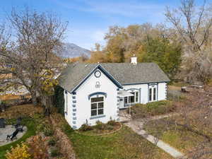 View of front of house featuring roof with shingles, stucco siding, a mountain view, a front lawn, and a chimney