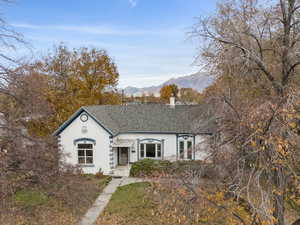 View of front of house featuring a shingled roof, a mountain view, stucco siding, and a chimney