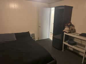 Bedroom with wooden walls and dark carpet