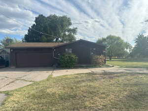 View of front of property featuring driveway, a front lawn, and a garage