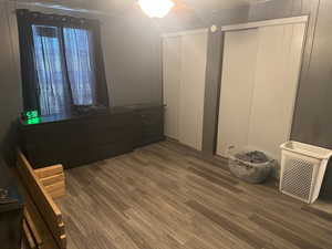 Bedroom with wood finished floors, two closets, and ceiling fan