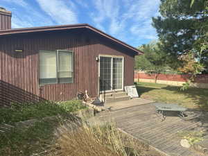View of property exterior with entry steps, a chimney, a deck, and a patio