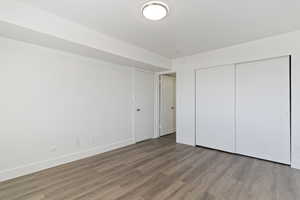 Unfurnished bedroom with wood finished floors and a closet