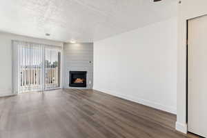 Unfurnished living room featuring a large fireplace, a textured ceiling, and dark wood-style floors