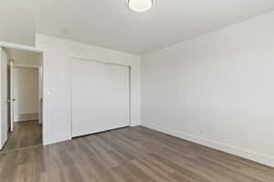 Unfurnished bedroom featuring wood finished floors and a closet