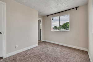 Carpeted spare room featuring baseboards and a textured ceiling
