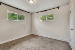 Carpeted empty room with baseboards and a textured ceiling