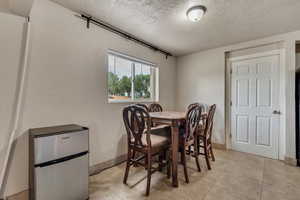 Dining room with a textured ceiling, light tile patterned floors, and a textured wall