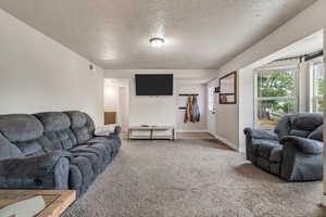 Carpeted living area featuring a textured ceiling and baseboards