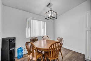 Dining room with wood finished floors and a chandelier