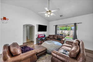 Living room featuring arched walkways, wood finished floors, a ceiling fan, and high vaulted ceiling