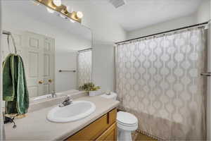 Full bath featuring vanity, shower / tub combo with curtain, and a textured ceiling