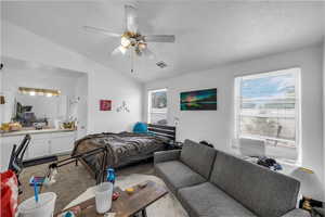Bedroom featuring vaulted ceiling, carpet, a textured ceiling, and ceiling fan