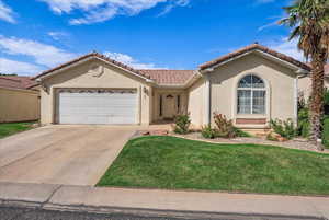 Mediterranean / spanish house featuring stucco siding, an attached garage, a tiled roof, concrete driveway, and a front yard