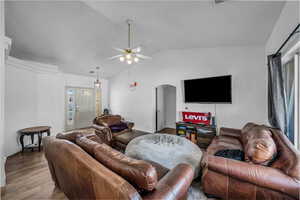 Living room with arched walkways, vaulted ceiling, wood finished floors, and ceiling fan