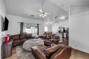 Living area with wood finished floors, vaulted ceiling, and ceiling fan