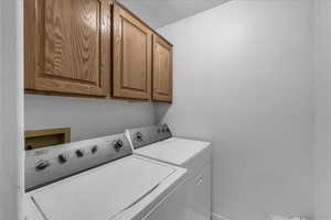 Washroom with cabinet space, independent washer and dryer, and a textured ceiling